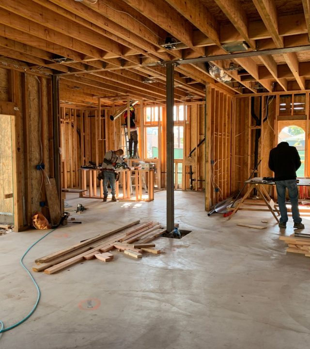 Workers constructing a house framework, showcasing interior carpentry and building process.